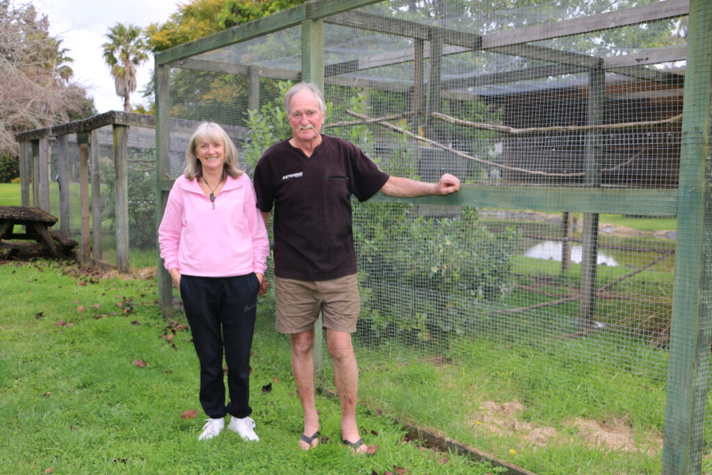 Woman and man standing in front of bird enclosure